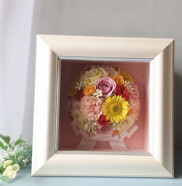 結婚式で使用したピンクのウェディングブーケを、立体的なラウンドデザインで額に保存した制作事例です。バラやガーベラ、カーネーションを生かしてお仕立てしました。