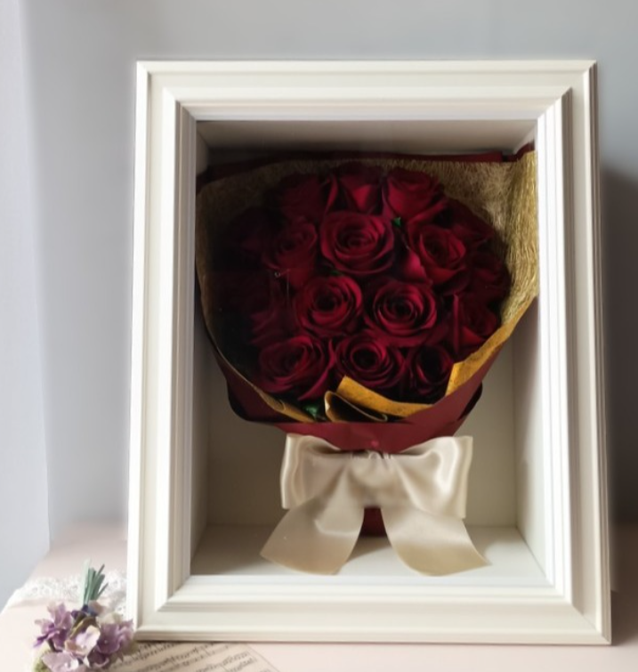 赤バラの花束をラッピングと白いリボンも一緒に白い額へ保存した立体ドライ加工作品